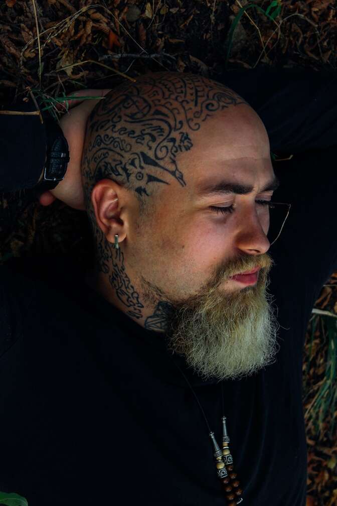Typ mit Glatze und Tattoo legt Kopf zur Seite, schläft