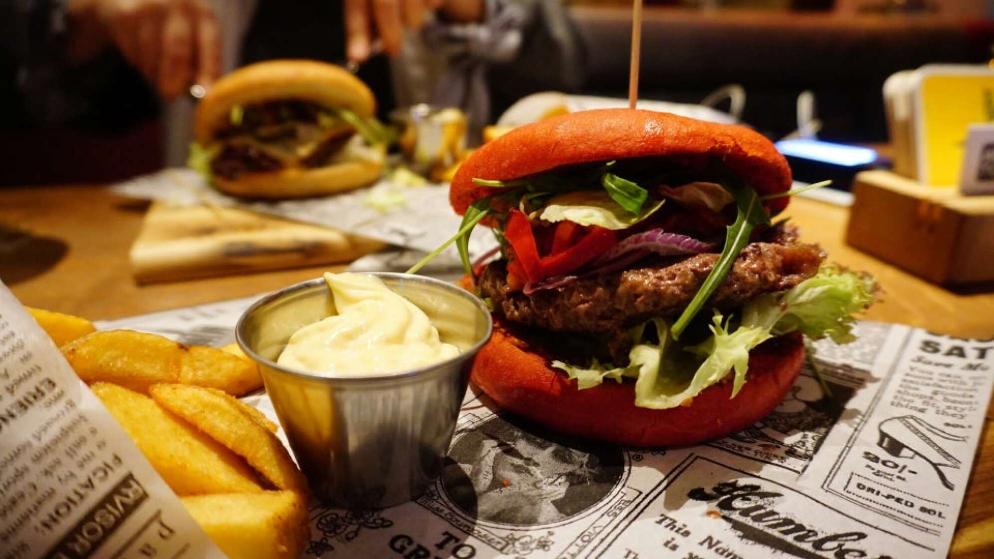 zwei Burger bei Addicted to Rock Bar & Burger plus Pommes und Sauce auf Zeitungspapier