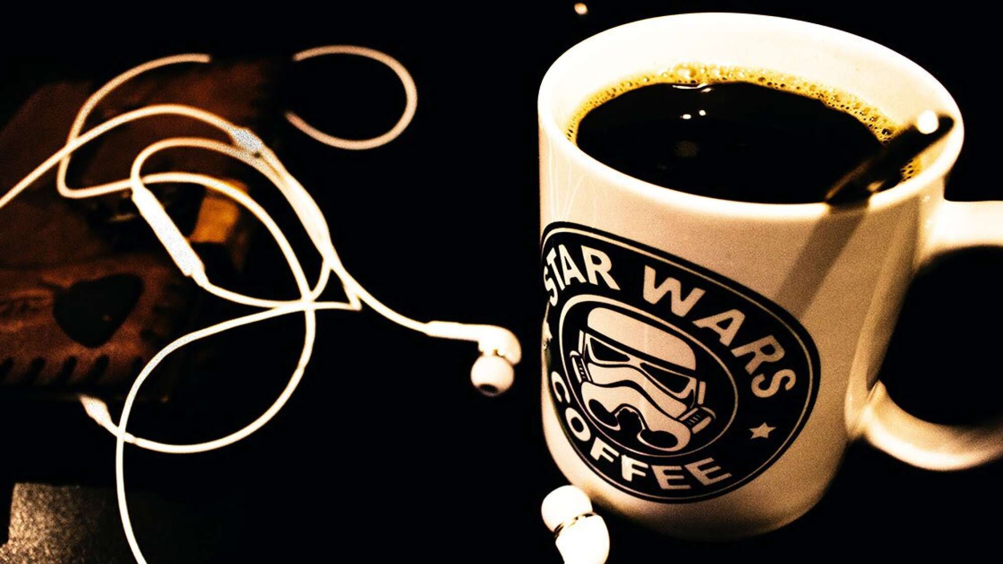 Star Wars Tasse mit Kaffee gefüllt und Kopfhörer daneben