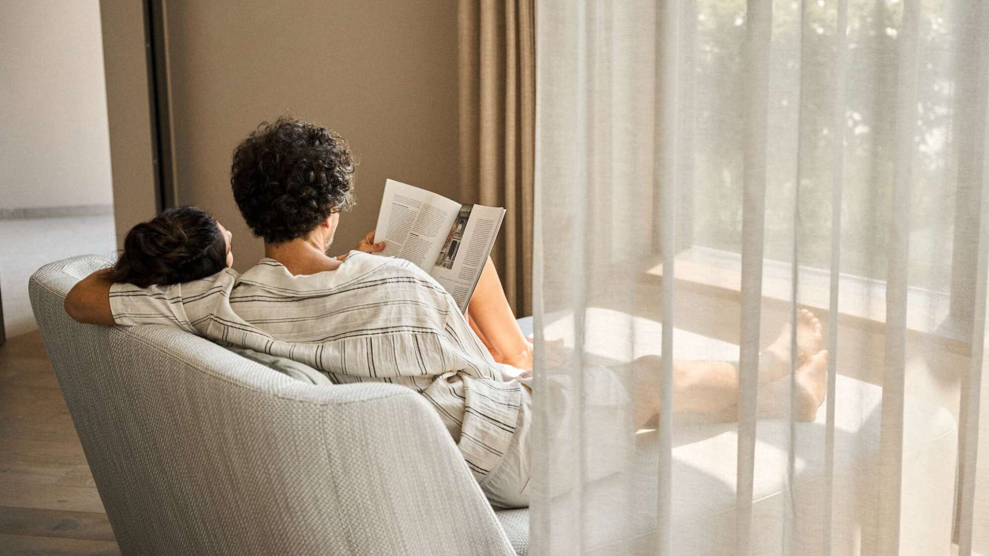ein Mann und eine Frau von hinten auf einer Liege, sie lesen gemeinsam eine Zeitschrift