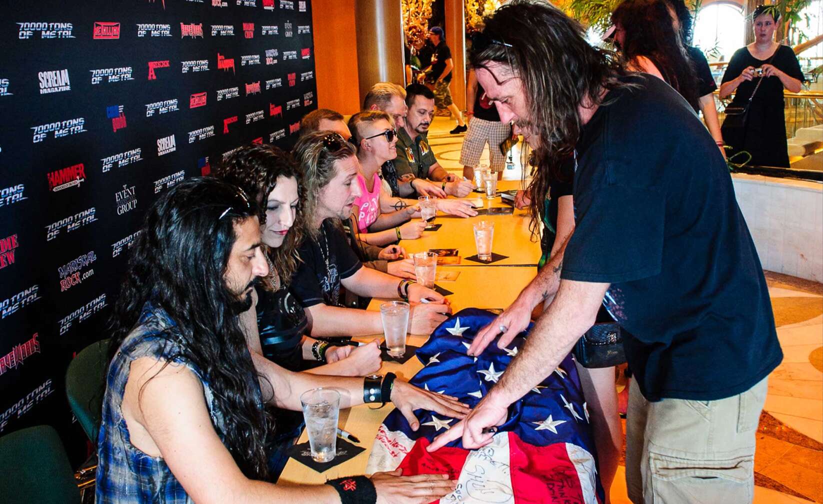 Bilder der 70000 Tons of Metal - Beim Meet & Greet unterschreibt die Band eine amerikansiche Flagge
