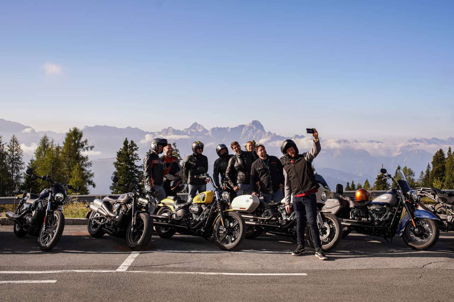 Gruppe von Harley-Davidson-Fahrerinnen und -Fahrern macht ein Selfie mit ihren Motorrädern auf einem Pass in Kärnten, im Hintergrund die Alpen rund um den Faaker See während der European Bike Week.