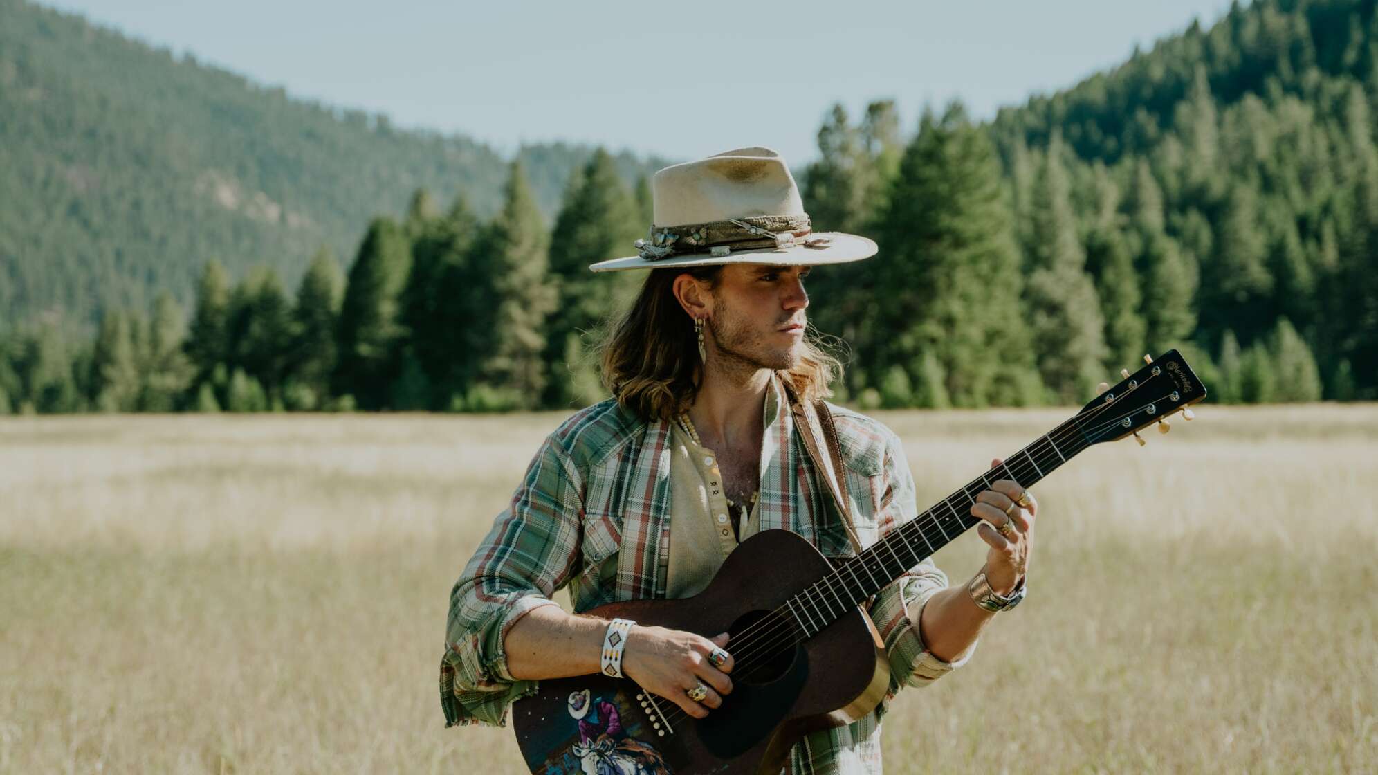 der Sänger von Kaleo steht mit Gitarre in einem Getreidefeld