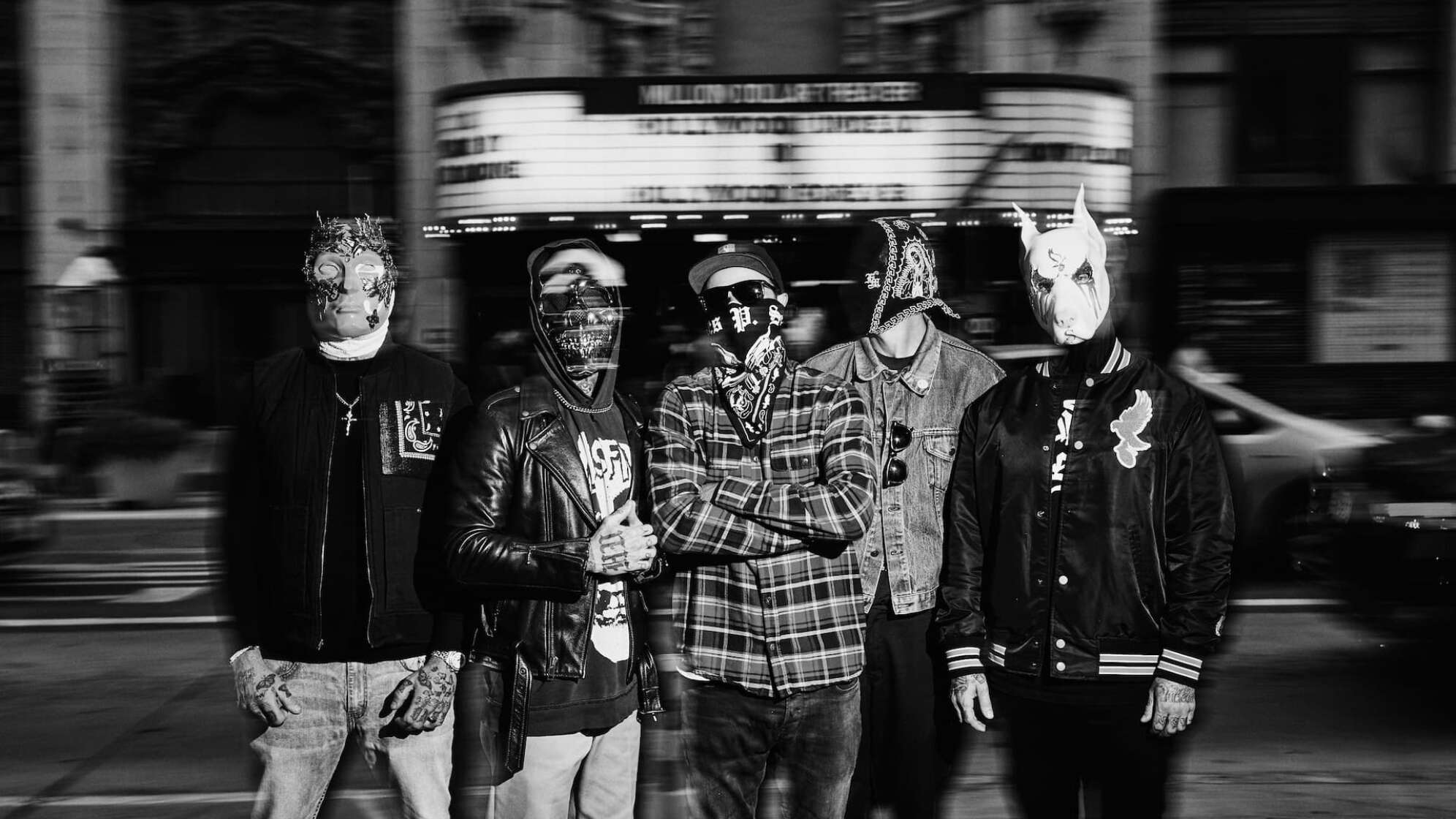 die vier Bandmitglieder von Hollywood Undead in Schwarz-Weiß vor einem Veranstaltungsort
