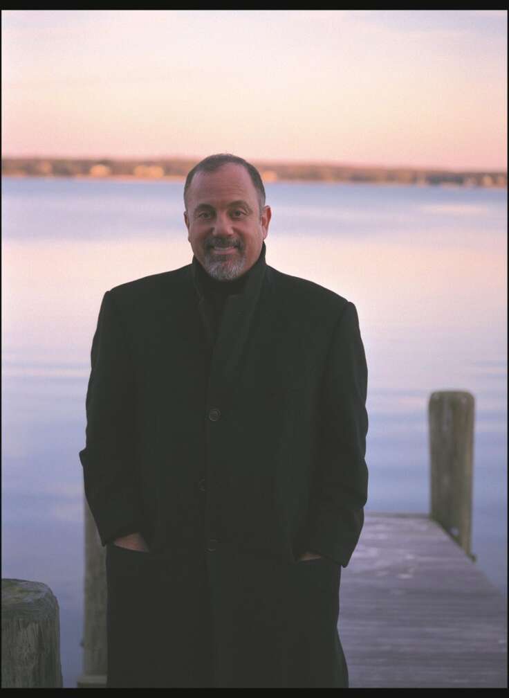 Porträt von Billy Joel vor See im Sonnenuntergang, lächelnd