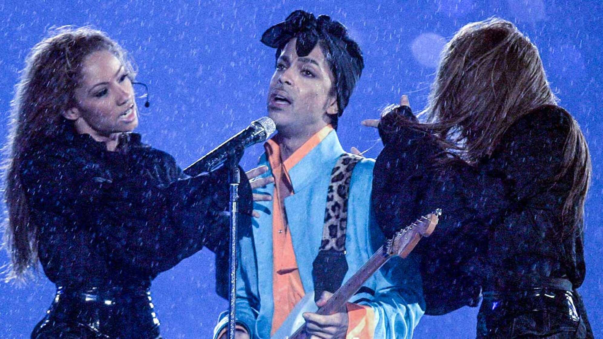 Prince mit zwei Tänzerinnen bei seinem Superbowl-Auftritt im Regen