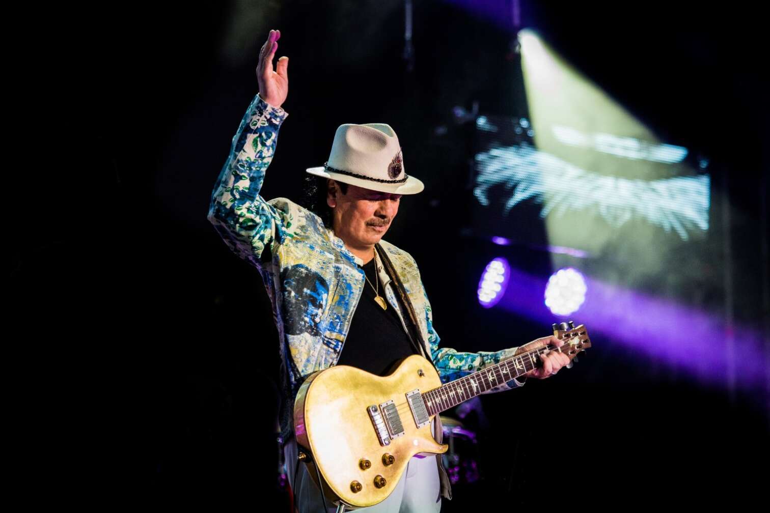 Carlos Santana winkend mit Gitarre auf der Bühne